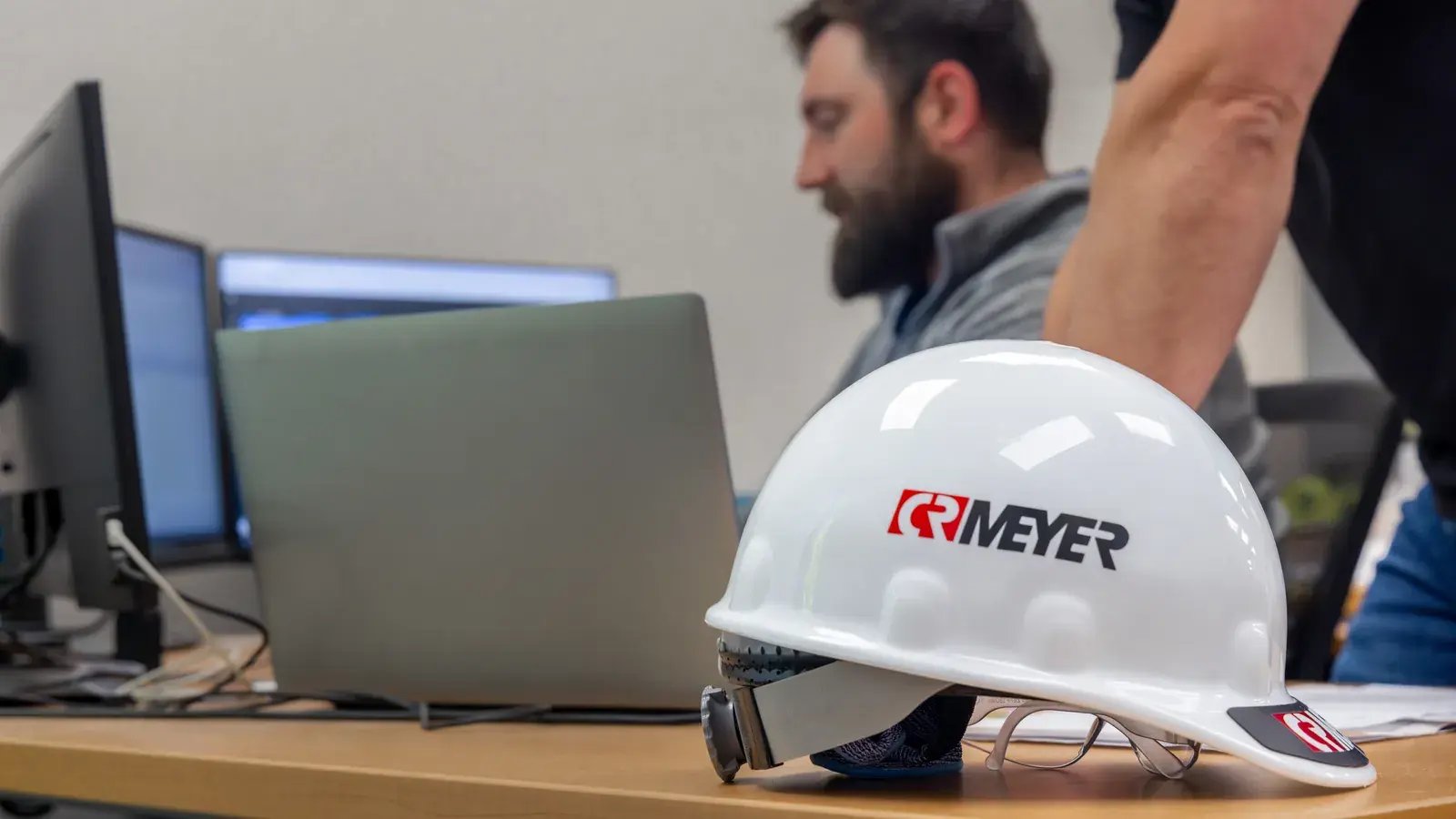 hard hat on desk man working on laptop