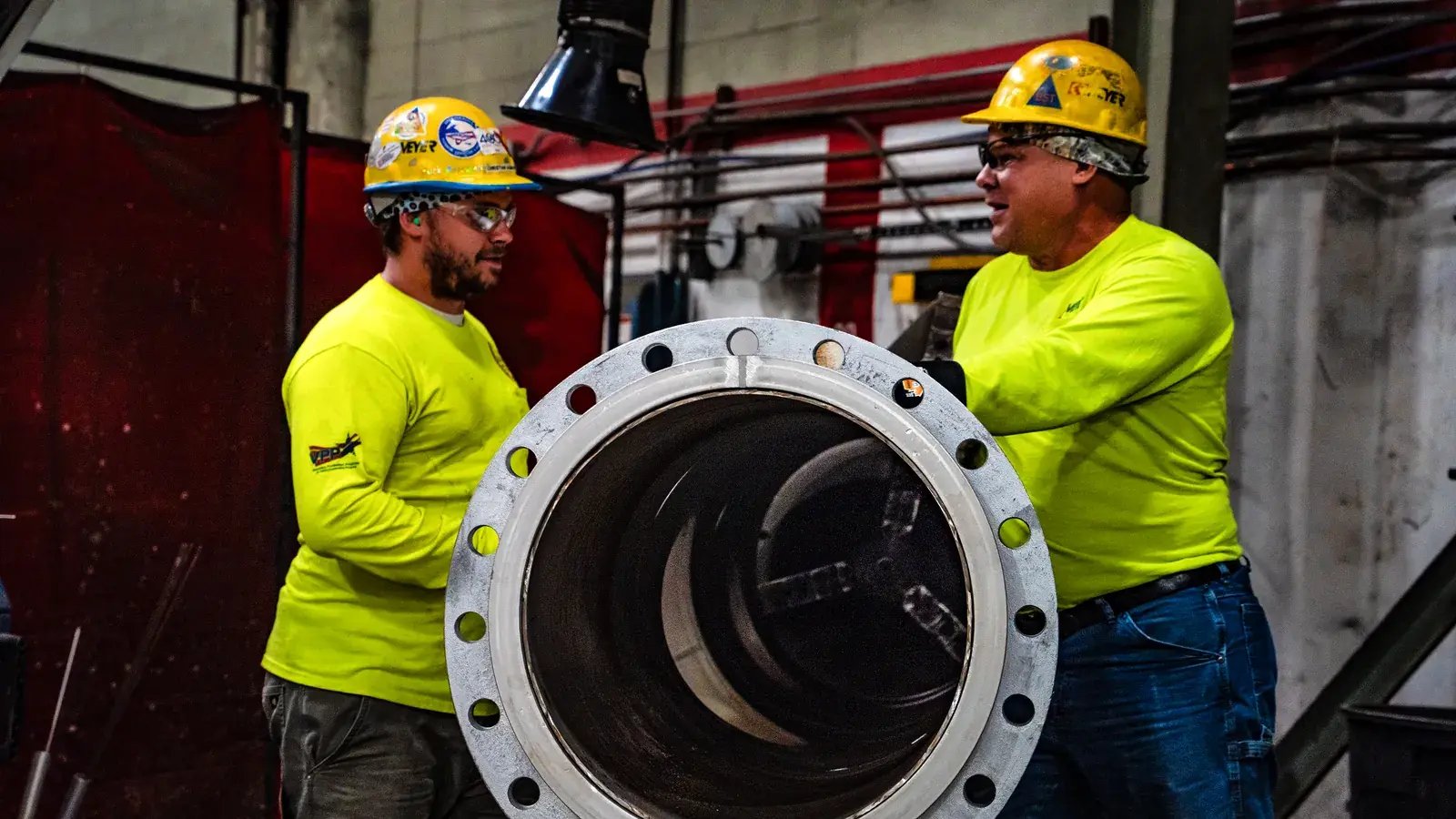 industrial workers inspecting large pipe