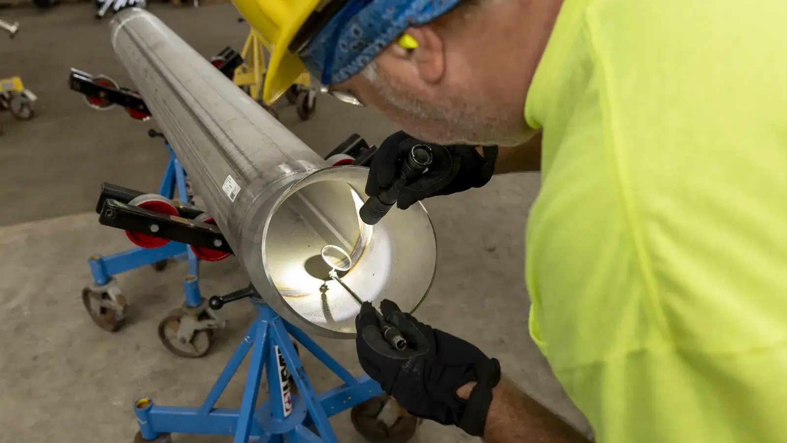 worker inspecting pipe weld interior with tools