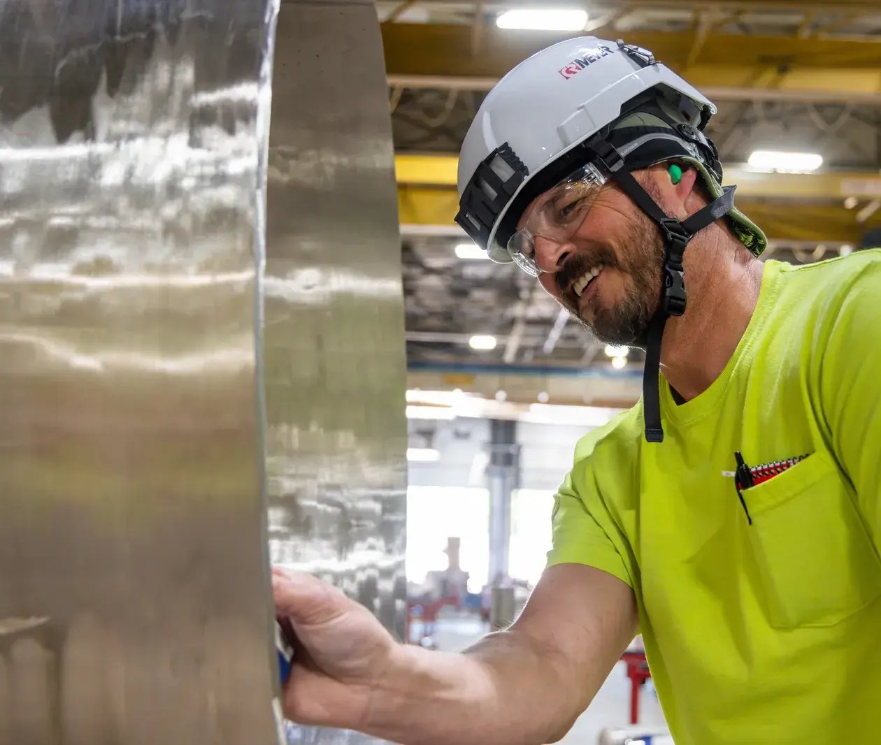 smiling worker inspecting metal part factory