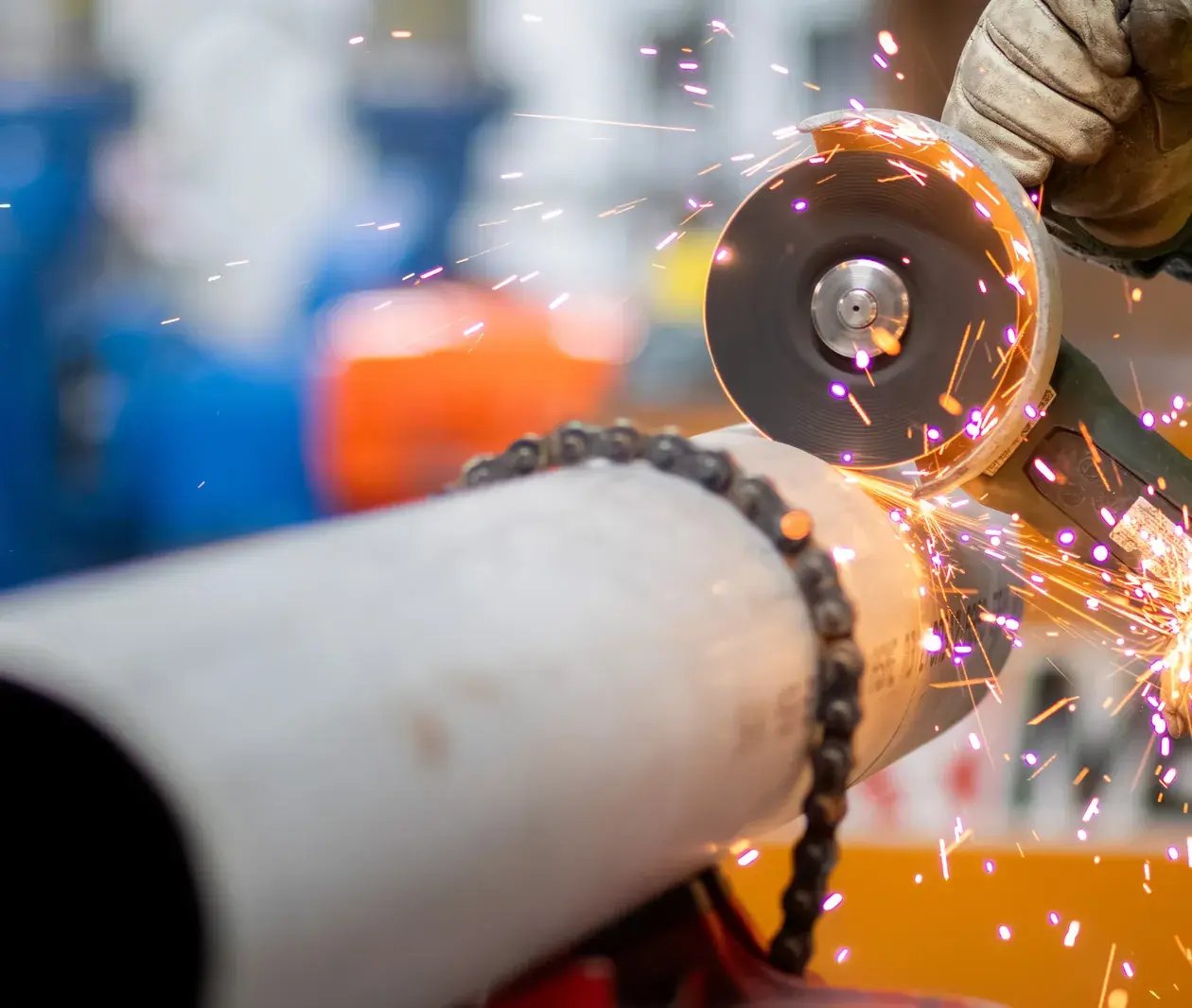 worker grinding pipe with sparks